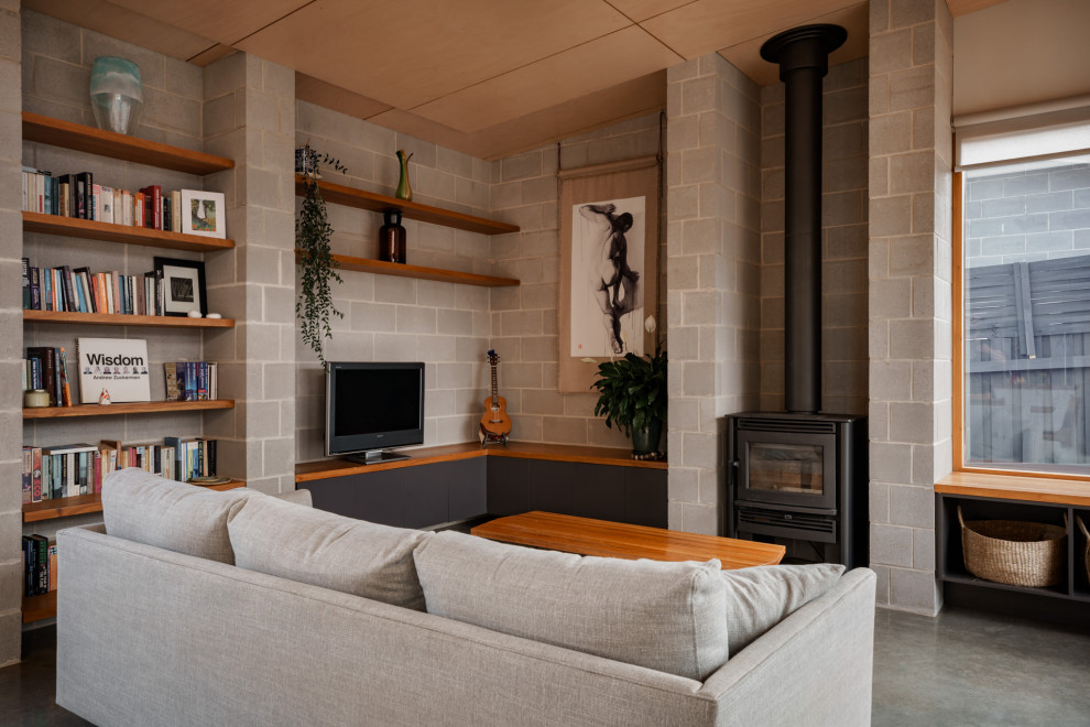 Inspiration for a mid-sized midcentury open concept living room in Geelong with a library, grey walls, concrete floors, a brick fireplace surround, a freestanding tv, grey floor, timber and brick walls.