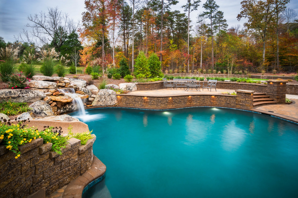 Photo of a mid-sized transitional backyard pool in Charlotte with a hot tub and brick pavers.