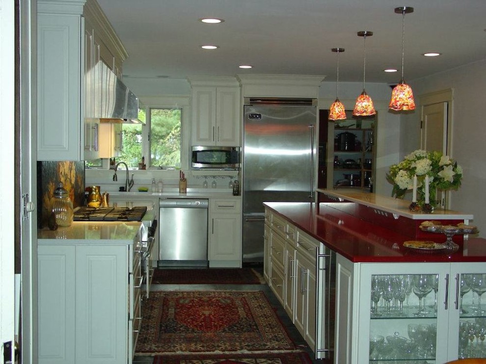 Photo of a mid-sized traditional galley open plan kitchen in New York with an undermount sink, raised-panel cabinets, white cabinets, quartz benchtops, black splashback, mosaic tile splashback, stainless steel appliances, slate floors, with island and red benchtop.