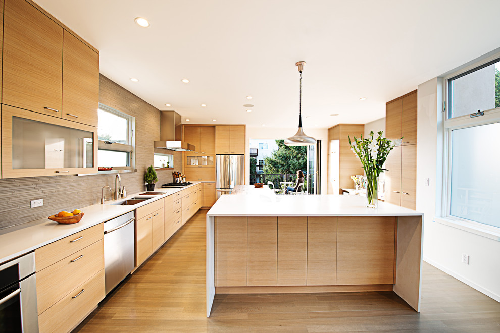 Modern separate kitchen in San Francisco with stainless steel appliances, flat-panel cabinets, light wood cabinets, beige splashback and matchstick tile splashback.