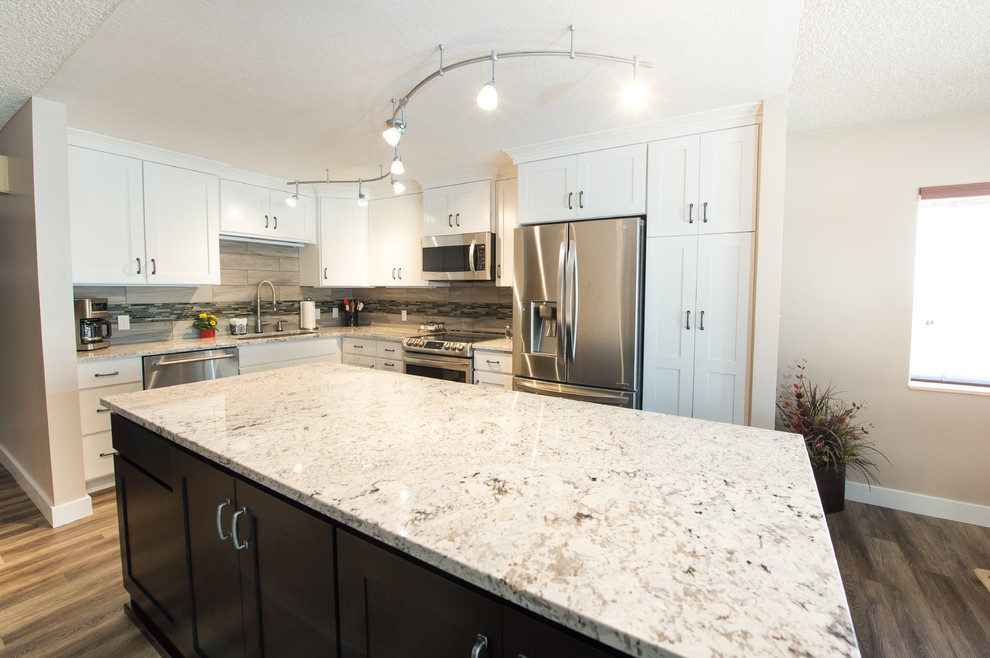 Inspiration for a small transitional l-shaped laminate floor and brown floor open concept kitchen remodel with an undermount sink, shaker cabinets, white cabinets, granite countertops, beige backsplash, matchstick tile backsplash, stainless steel appliances and an island