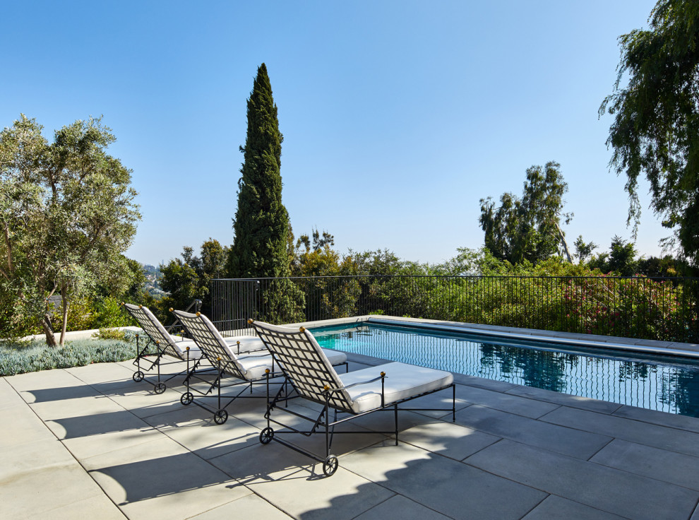 Imagen de piscina alargada mediterránea grande rectangular en patio trasero con paisajismo de piscina y adoquines de hormigón