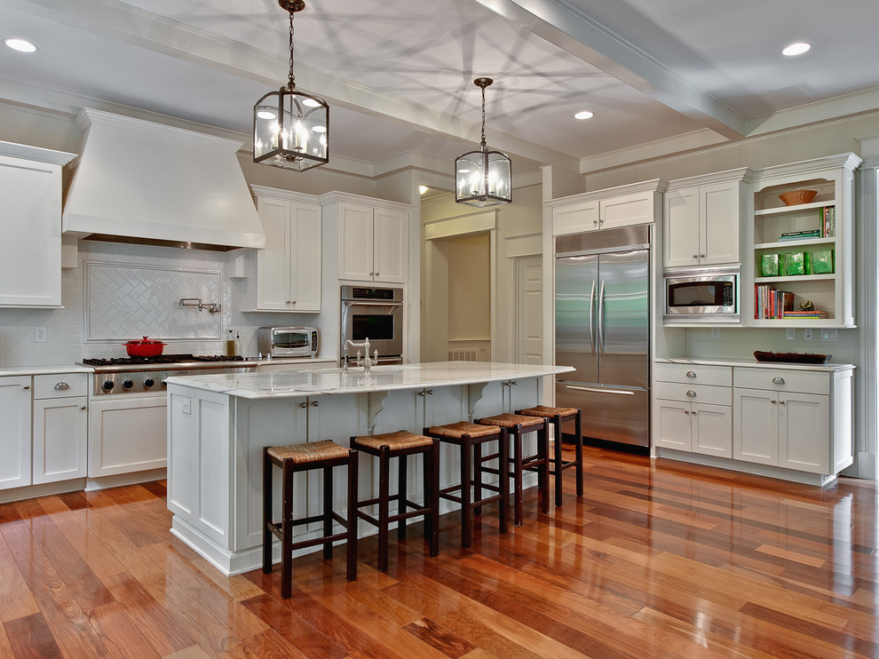 This is an example of an expansive transitional u-shaped eat-in kitchen in Charlotte with an undermount sink, white cabinets, white splashback, stainless steel appliances, medium hardwood floors, with island, shaker cabinets, marble benchtops and subway tile splashback.