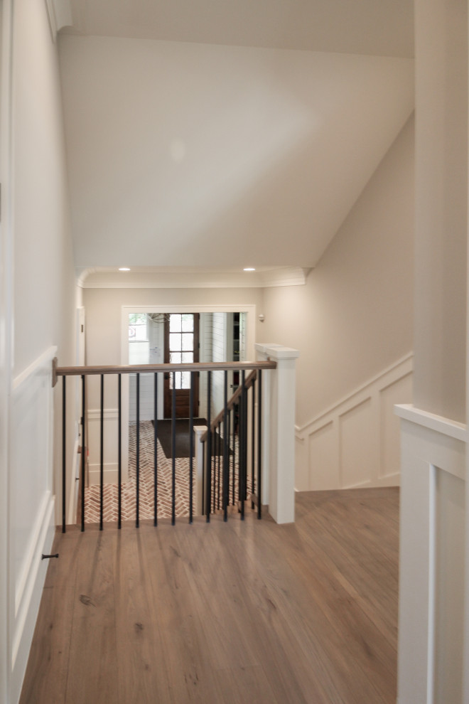 Photo of a large transitional wood u-shaped staircase in DC Metro with wood risers, wood railing and decorative wall panelling.