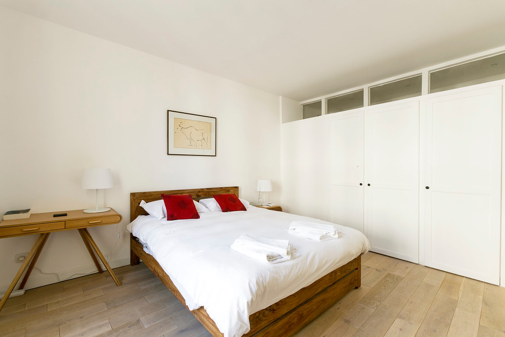 Photo of a large scandinavian master bedroom in Paris with white walls and light hardwood floors.