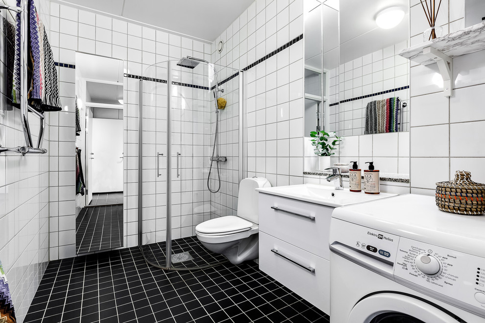 Large scandinavian 3/4 bathroom in Stockholm with flat-panel cabinets, white cabinets, black floor, a corner shower, a two-piece toilet, black tile, black and white tile, multi-coloured tile and white tile.