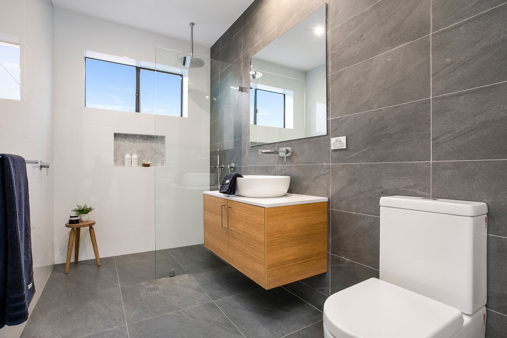 Photo of a mid-sized contemporary 3/4 bathroom in Sydney with white tile, porcelain tile, ceramic floors, engineered quartz benchtops, grey floor, an open shower, flat-panel cabinets, medium wood cabinets, a curbless shower, a two-piece toilet and a vessel sink.