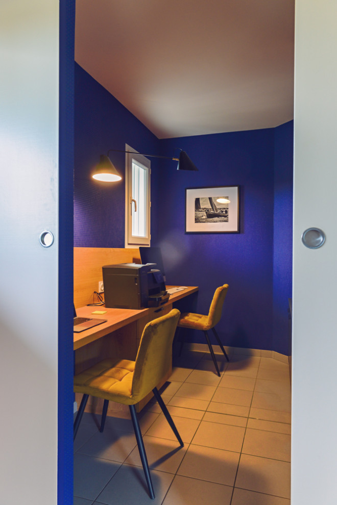 На фото: рабочее место среднего размера в современном стиле с синими стенами, полом из керамической плитки, встроенным рабочим столом, серым полом и обоями на стенах с