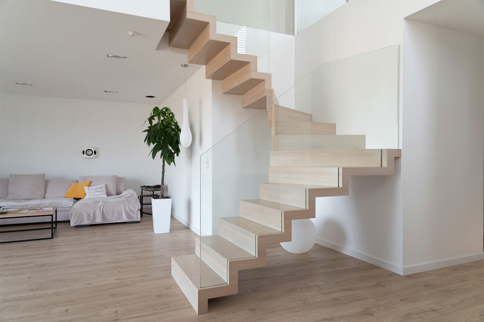 Diseño de escalera curva moderna con escalones de vidrio, contrahuellas de madera y barandilla de vidrio