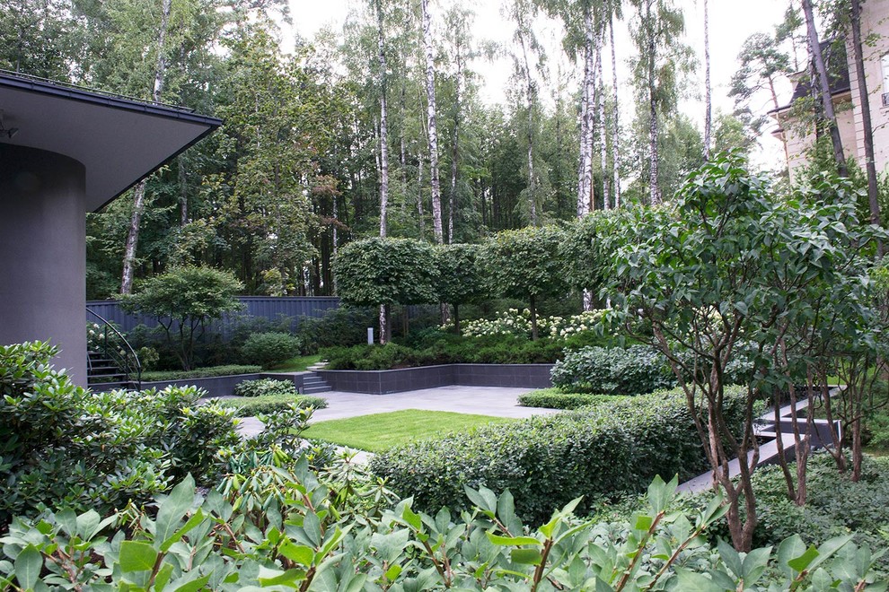 Design ideas for a contemporary courtyard partial sun formal garden in Moscow with a retaining wall and natural stone pavers.