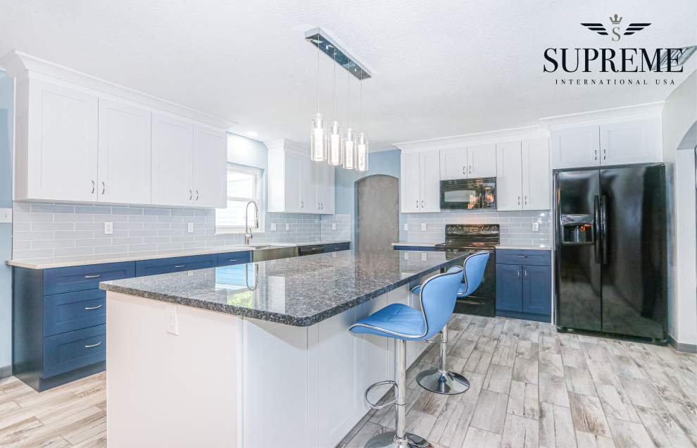 Inspiration for a mid-sized transitional l-shaped eat-in kitchen in Tampa with an undermount sink, shaker cabinets, blue cabinets, quartz benchtops, grey splashback, ceramic splashback, black appliances, vinyl floors, with island, brown floor, white benchtop and coffered.