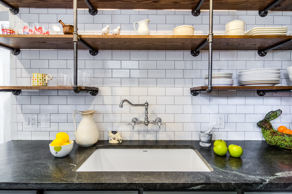 Small industrial galley separate kitchen in Boston with an undermount sink, shaker cabinets, grey cabinets, white splashback, subway tile splashback, no island, soapstone benchtops, stainless steel appliances, slate floors and brown floor.
