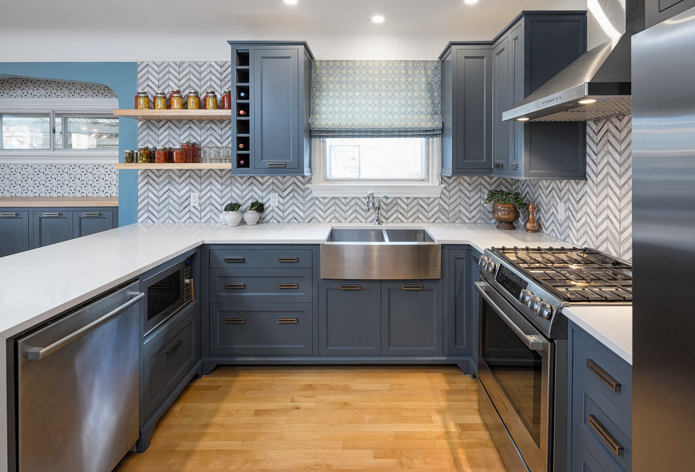 Transitional u-shaped kitchen in Ottawa with a farmhouse sink, recessed-panel cabinets, blue cabinets, multi-coloured splashback, stainless steel appliances, medium hardwood floors and no island.