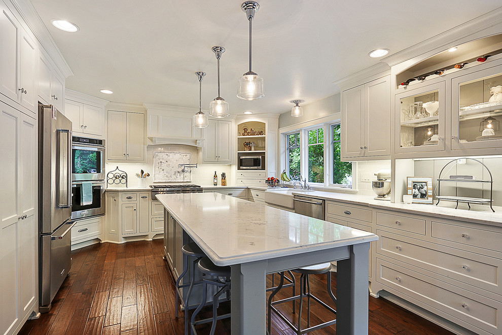 Transitional kitchen photo with white cabinets, white backsplash and an island