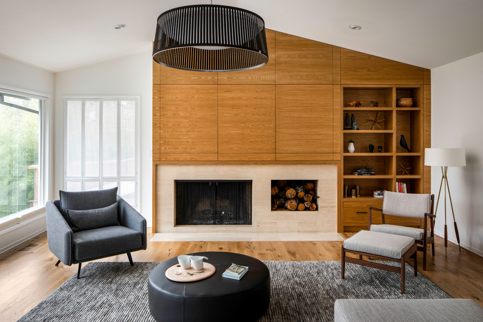This is an example of a midcentury living room in Portland with white walls, light hardwood floors, a standard fireplace and a stone fireplace surround.