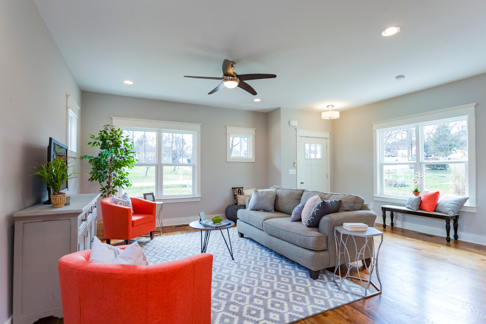 This is an example of a small transitional open concept living room in Nashville with grey walls, light hardwood floors, no fireplace and a freestanding tv.