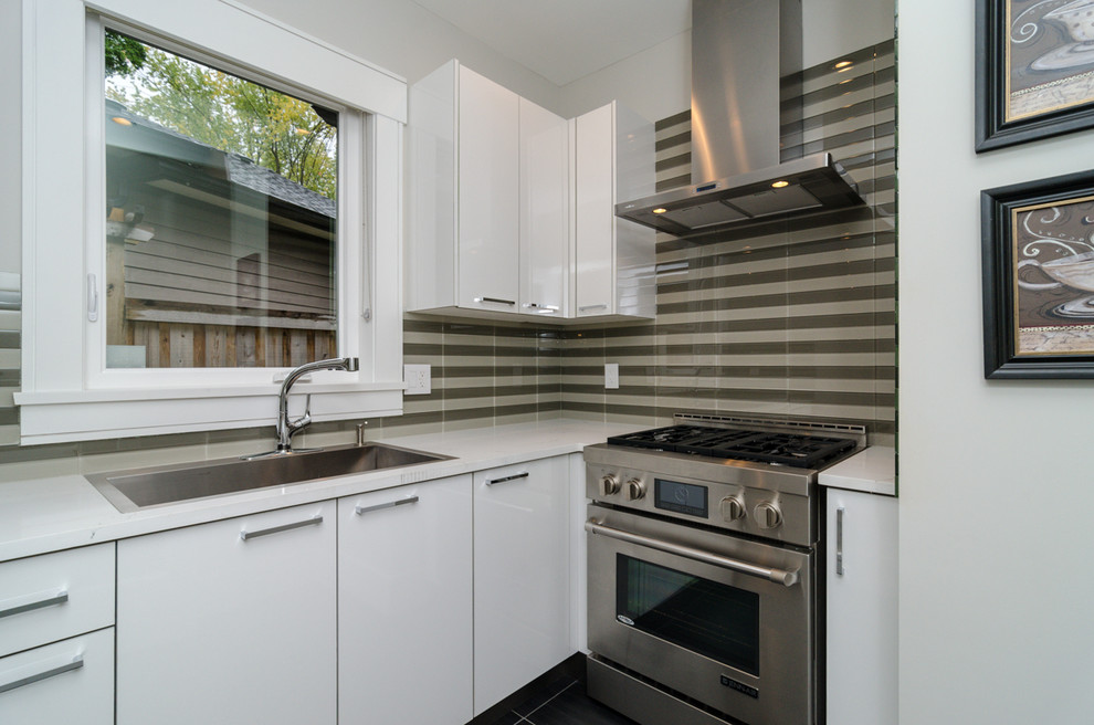 Mid-sized modern l-shaped eat-in kitchen in Vancouver with flat-panel cabinets, white cabinets, multi-coloured splashback, stainless steel appliances, with island, a drop-in sink, matchstick tile splashback, slate floors and marble benchtops.