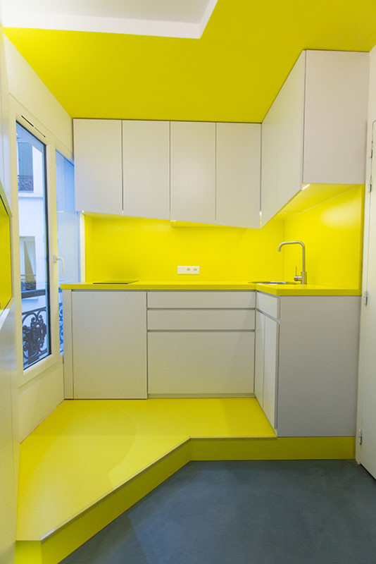 Photo of a mid-sized contemporary l-shaped open plan kitchen in Paris with an undermount sink, white cabinets, yellow splashback and panelled appliances.