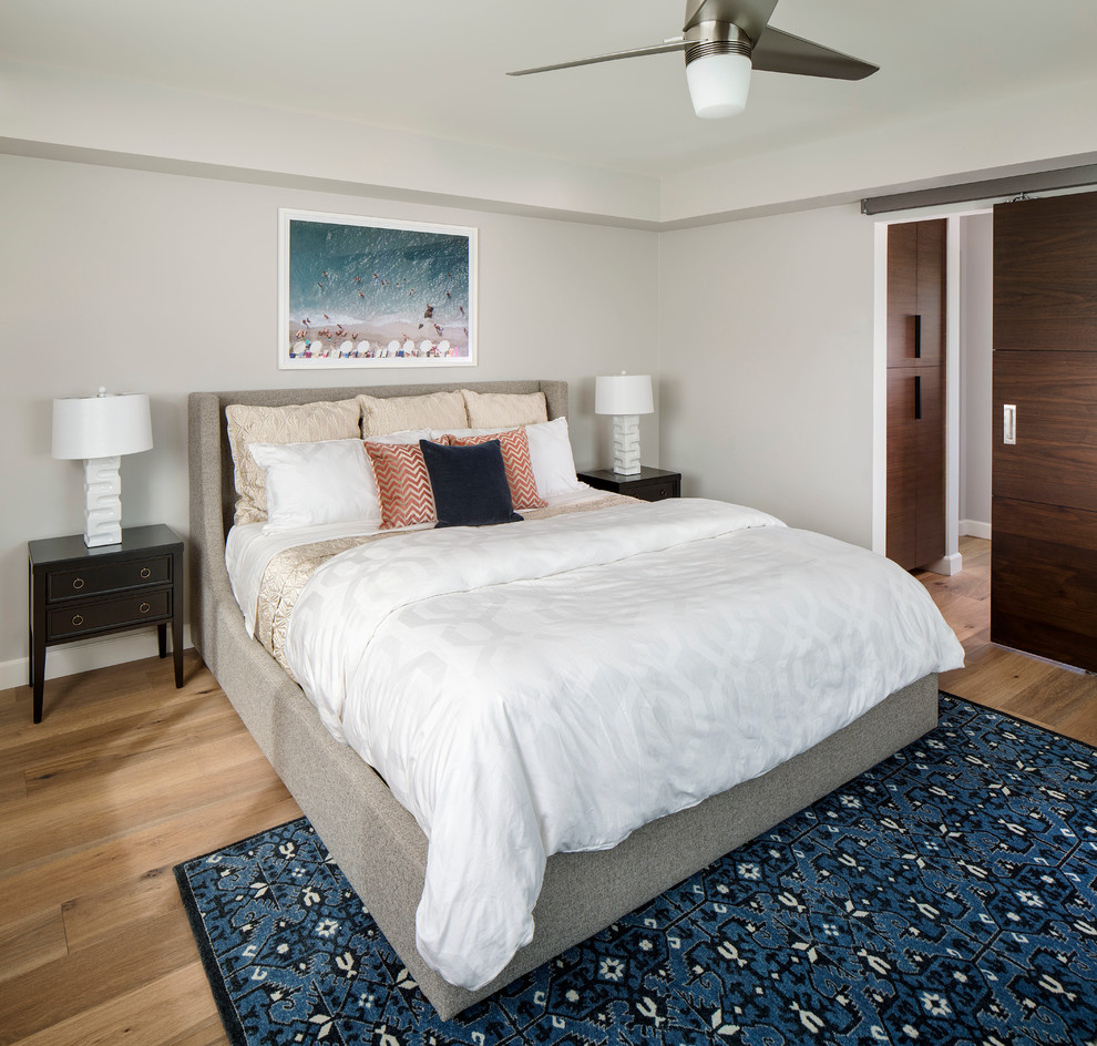 This is an example of a mid-sized midcentury guest bedroom in San Diego with white walls and light hardwood floors.