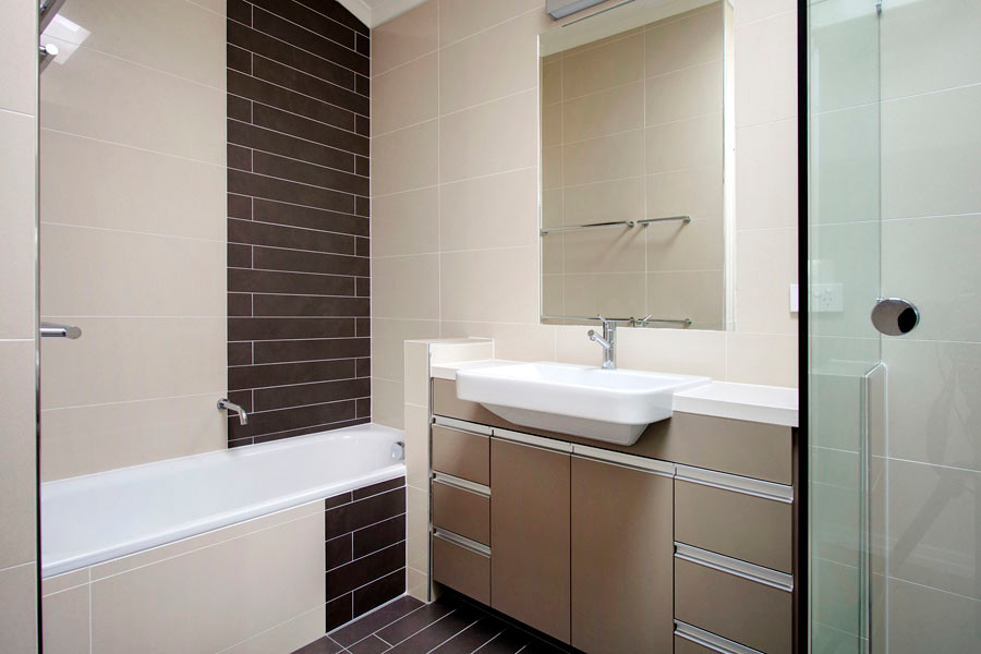 Design ideas for an expansive contemporary kids bathroom in Brisbane with flat-panel cabinets, beige cabinets, an alcove tub, a corner shower, a wall-mount toilet, beige tile, porcelain tile, beige walls, a drop-in sink, brown floor and a hinged shower door.