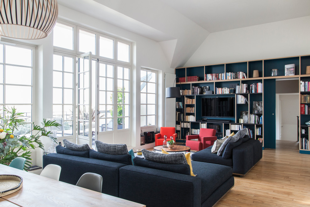 Photo of an expansive contemporary open concept living room in Paris with a library, white walls, no fireplace, a built-in media wall, brown floor and light hardwood floors.