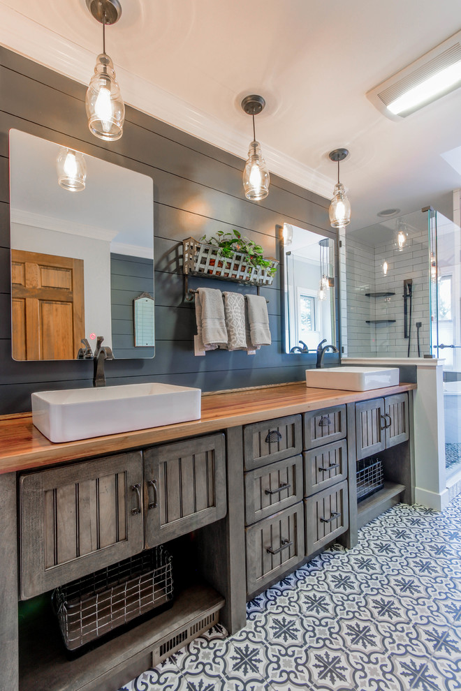 Inspiration for a mid-sized country master bathroom in Detroit with recessed-panel cabinets, brown cabinets, a freestanding tub, a corner shower, blue walls, mosaic tile floors, a vessel sink, wood benchtops, blue floor, a hinged shower door and brown benchtops.