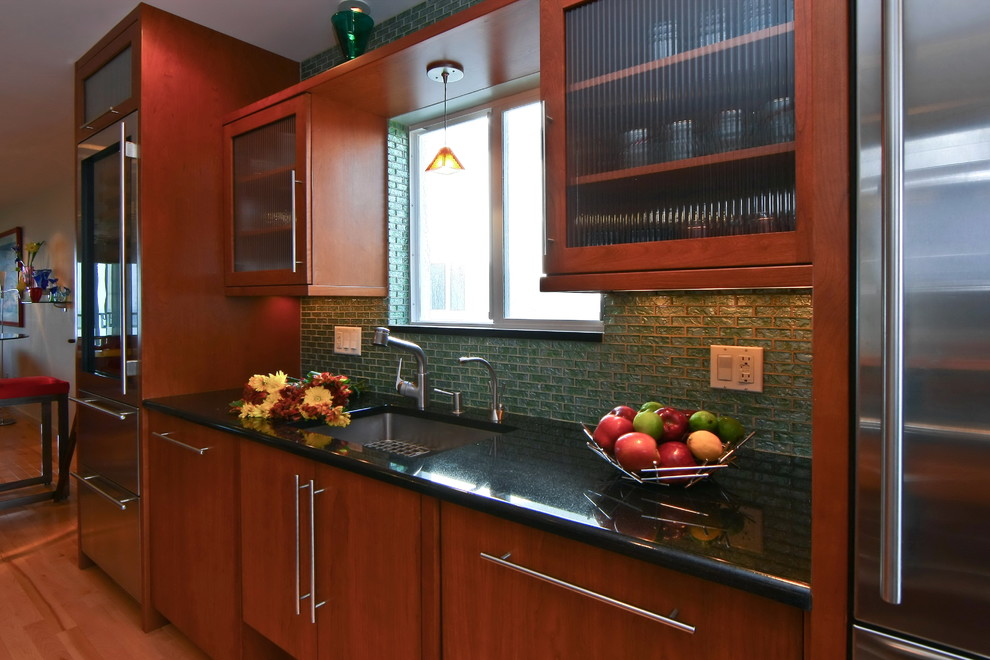 Large transitional l-shaped light wood floor eat-in kitchen photo with an undermount sink, flat-panel cabinets, medium tone wood cabinets, green backsplash, glass tile backsplash, stainless steel appliances and an island