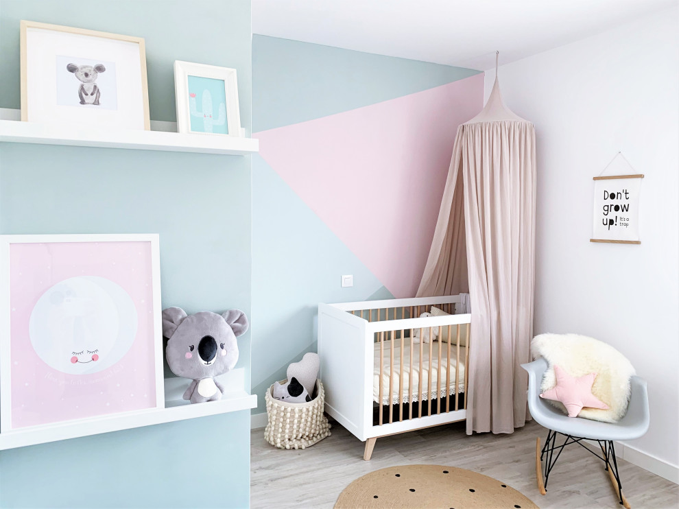 Photo of a contemporary nursery for girls in Madrid with multi-coloured walls, light hardwood floors and grey floor.