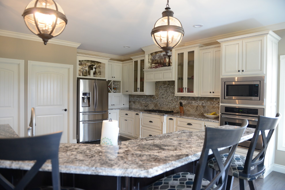 Inspiration for a huge transitional l-shaped medium tone wood floor eat-in kitchen remodel in Chicago with a farmhouse sink, raised-panel cabinets, white cabinets, granite countertops, gray backsplash, glass tile backsplash, stainless steel appliances and an island