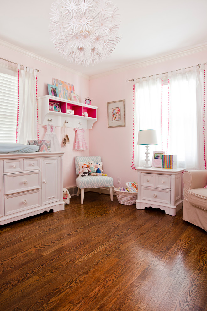Inspiration for a traditional nursery for girls in Kansas City with pink walls and medium hardwood floors.