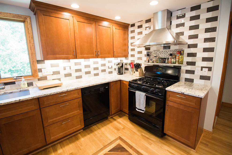 Example of a mid-sized transitional u-shaped medium tone wood floor eat-in kitchen design in Boston with an undermount sink, recessed-panel cabinets, medium tone wood cabinets, granite countertops, multicolored backsplash, subway tile backsplash, black appliances and a peninsula