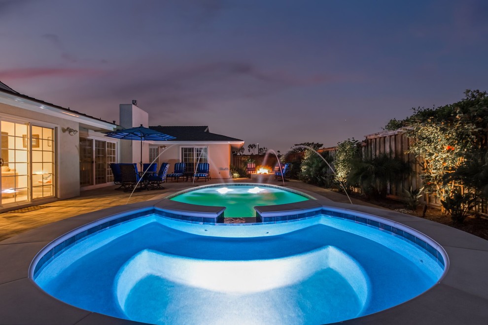 This is an example of a mid-sized transitional backyard round lap pool in Orange County with a hot tub and natural stone pavers.