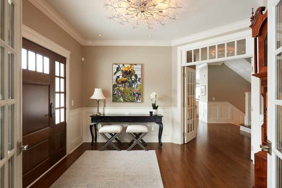 Inspiration for a traditional foyer in Edmonton with beige walls, medium hardwood floors, a single front door, a medium wood front door and brown floor.