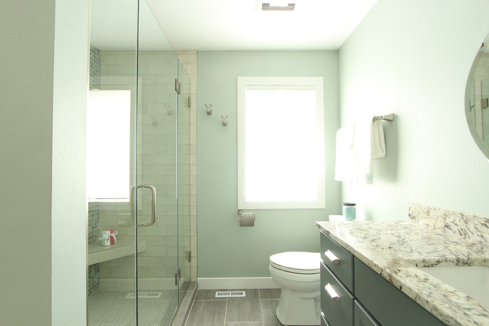 Mid-sized transitional 3/4 bathroom in Other with recessed-panel cabinets, blue cabinets, an alcove shower, a two-piece toilet, blue tile, glass sheet wall, blue walls, limestone floors, an undermount sink, granite benchtops, grey floor, a hinged shower door and white benchtops.
