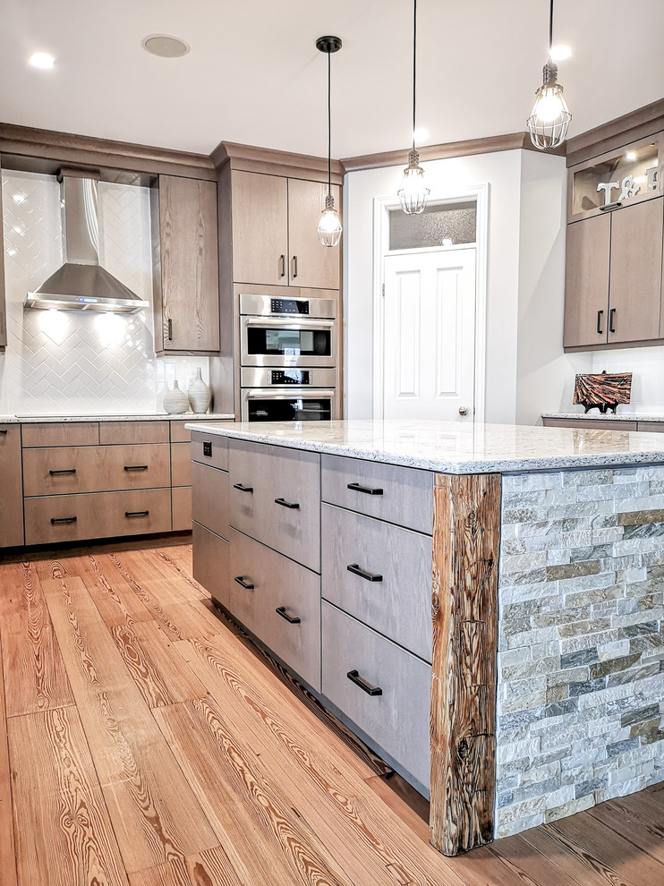 Inspiration for a large u-shaped light wood floor and brown floor eat-in kitchen remodel with an undermount sink, flat-panel cabinets, beige cabinets, quartz countertops, white backsplash, subway tile backsplash, stainless steel appliances, an island and white countertops