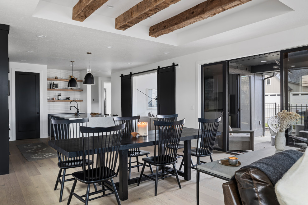 Inspiration for a mid-sized scandinavian open plan dining in Boise with white walls, light hardwood floors, a wood stove, a metal fireplace surround, beige floor and exposed beam.