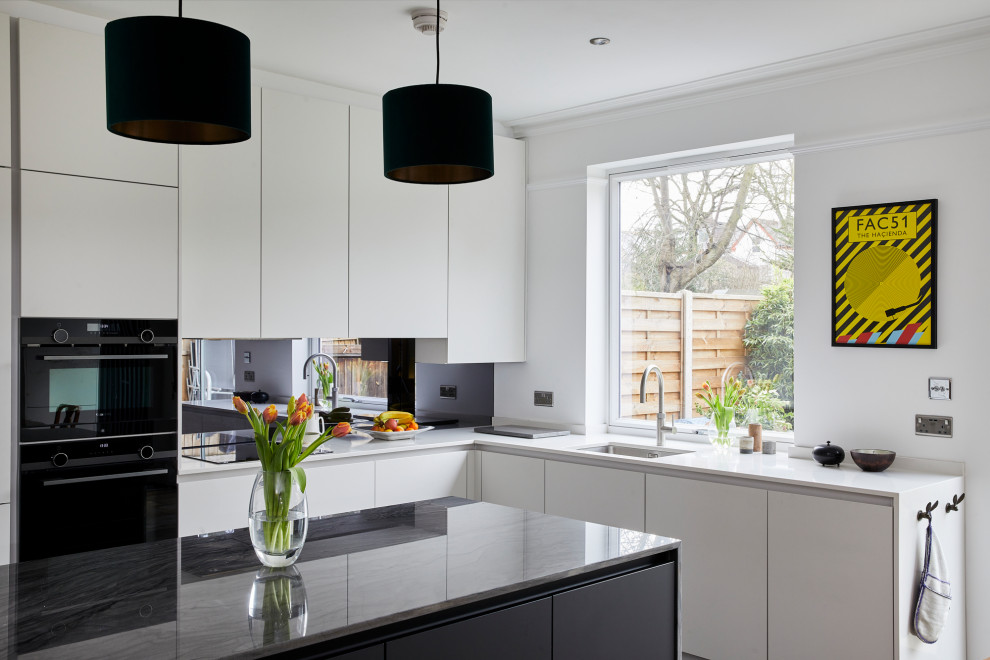 Design ideas for a medium sized contemporary l-shaped kitchen/diner in London with a submerged sink, flat-panel cabinets, white cabinets, quartz worktops, glass sheet splashback, black appliances, an island and white worktops.