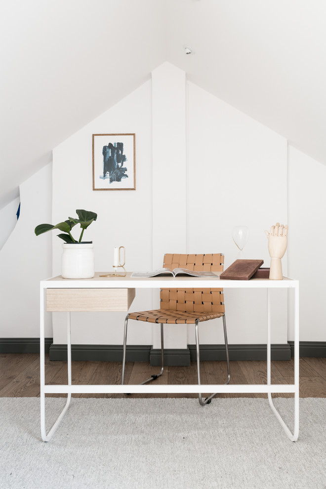 Scandinavian home office in Stockholm with white walls, a freestanding desk and brown floor.