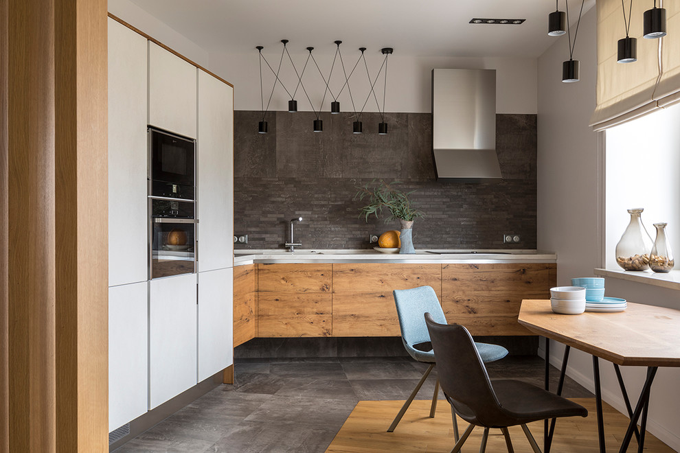 This is an example of a mid-sized contemporary l-shaped eat-in kitchen in Moscow with an undermount sink, flat-panel cabinets, medium wood cabinets, grey splashback, black appliances, no island and grey floor.