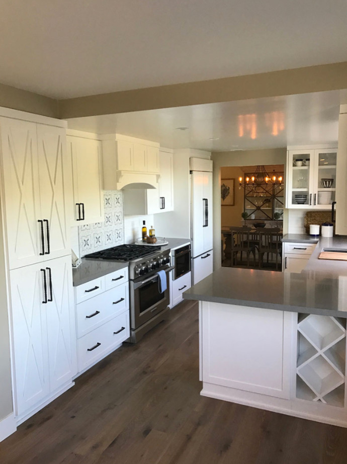 Small transitional single-wall eat-in kitchen in San Diego with raised-panel cabinets, white cabinets, laminate benchtops, white splashback, ceramic splashback, stainless steel appliances, dark hardwood floors, no island and brown floor.