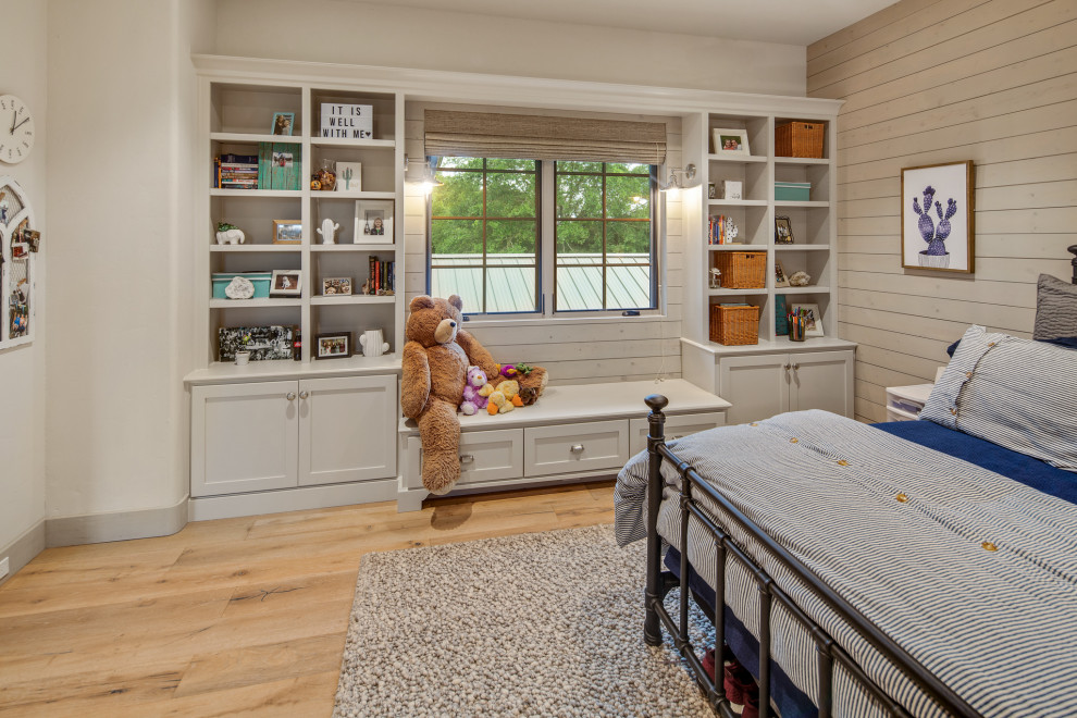 This is an example of a country gender-neutral kids' bedroom in Other with beige walls, medium hardwood floors and brown floor.