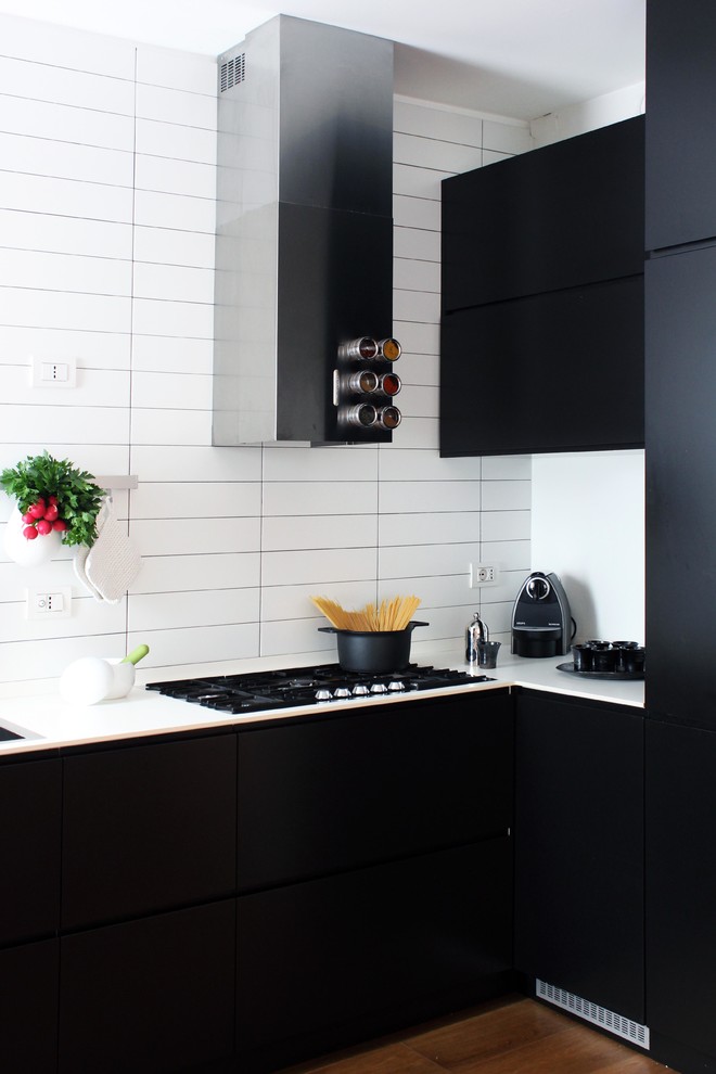 Inspiration for a small contemporary l-shaped kitchen in Milan with flat-panel cabinets, black cabinets, white splashback, ceramic splashback and dark hardwood floors.