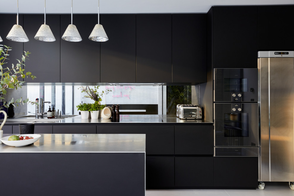 Einzeilige, Kleine Moderne Wohnküche mit flächenbündigen Schrankfronten, schwarzen Schränken, Edelstahl-Arbeitsplatte und Kücheninsel in London
