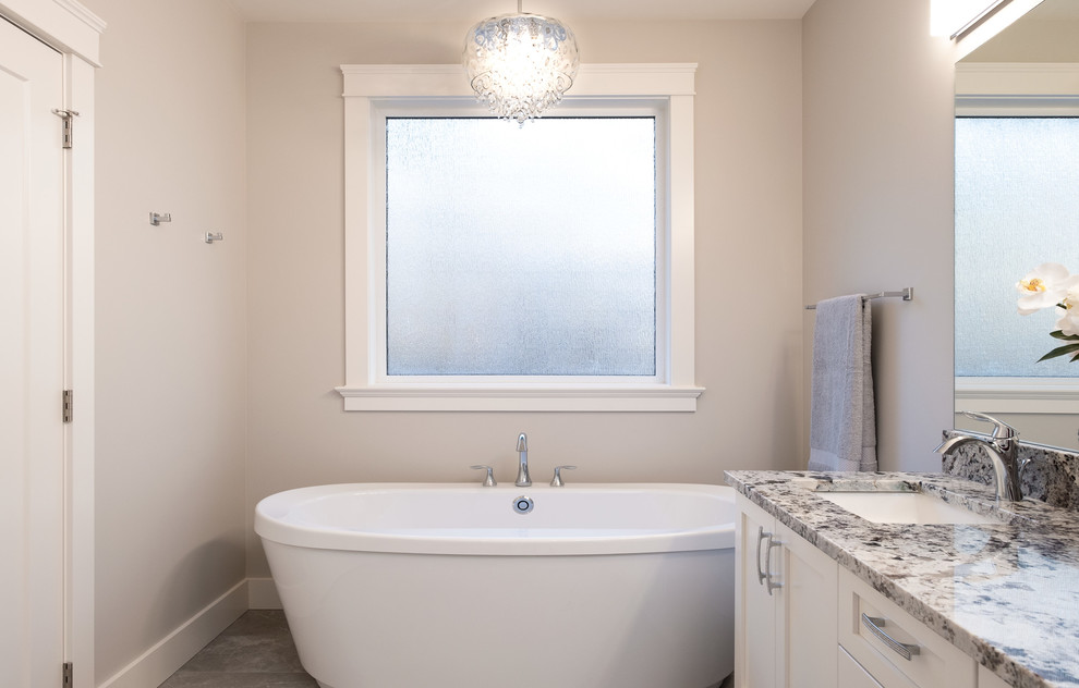 Large traditional master bathroom in Other with shaker cabinets, white cabinets, a freestanding tub, an alcove shower, a one-piece toilet, grey walls, porcelain floors, an undermount sink, granite benchtops, grey floor, a hinged shower door and multi-coloured benchtops.