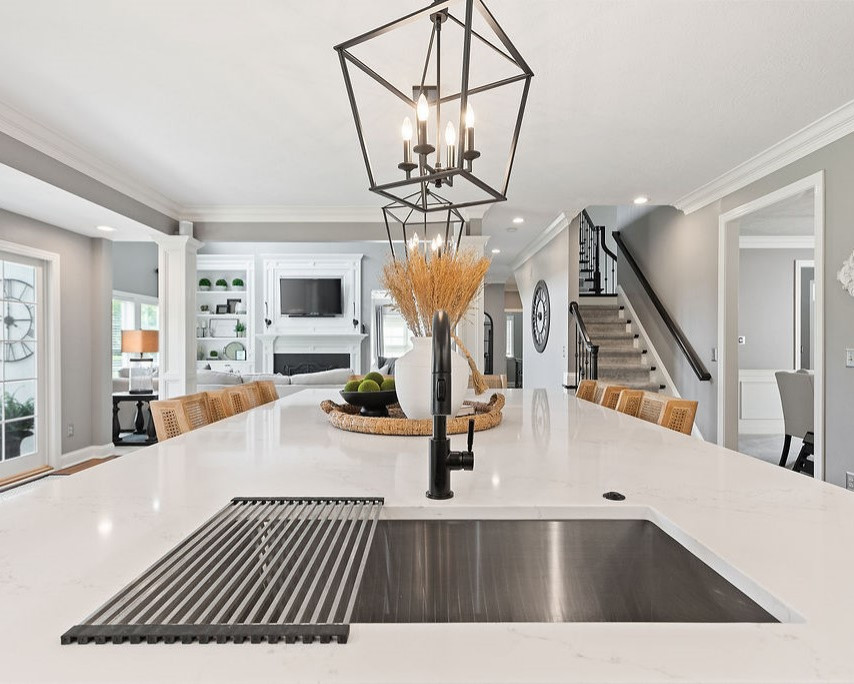 Design ideas for a large traditional l-shaped eat-in kitchen in Columbus with an undermount sink, recessed-panel cabinets, white cabinets, quartz benchtops, white splashback, engineered quartz splashback, stainless steel appliances, medium hardwood floors, with island and white benchtop.