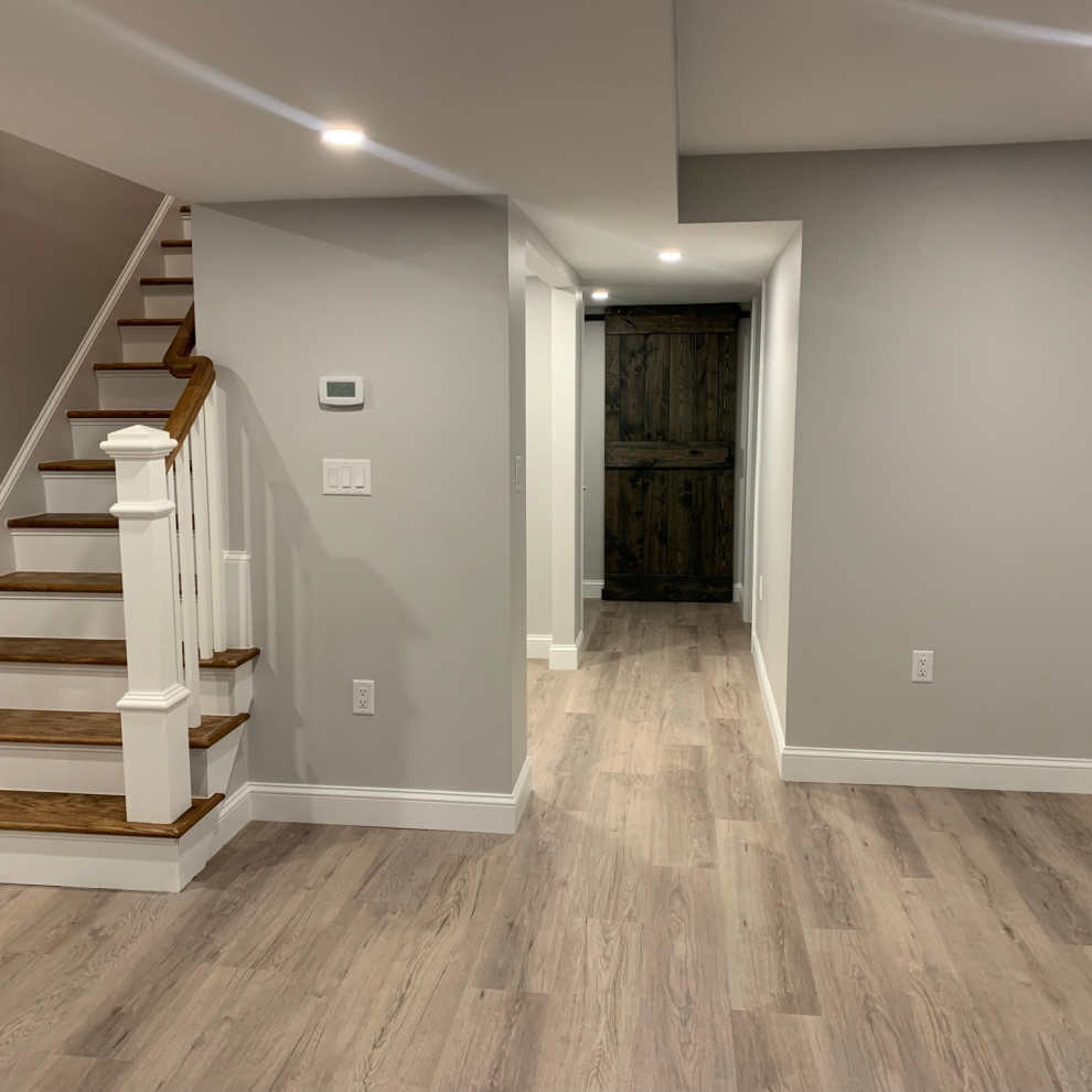 Photo of a mid-sized modern walk-out basement in Boston with grey walls, laminate floors and brown floor.