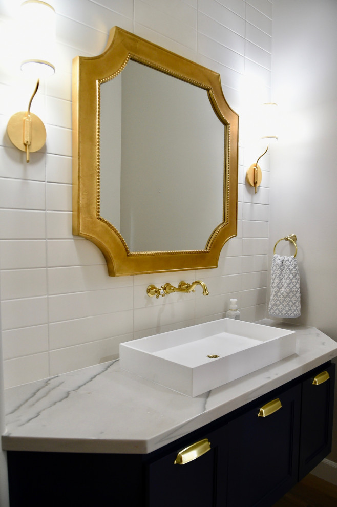 Mid-sized transitional powder room in Phoenix with shaker cabinets, blue cabinets, a two-piece toilet, white tile, subway tile, white walls, porcelain floors, a vessel sink, quartzite benchtops, beige floor, white benchtops and a floating vanity.