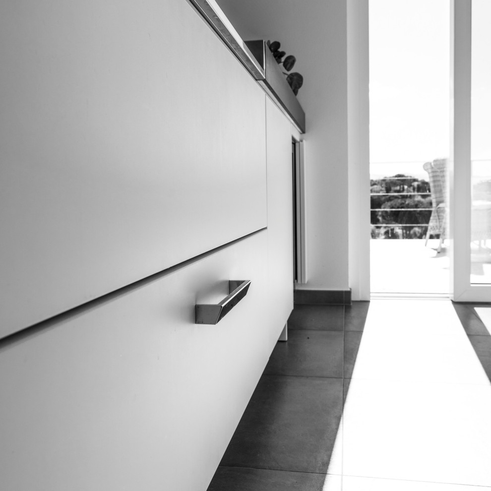 Bild på ett mycket stort funkis grå grått kök, med en integrerad diskho, luckor med profilerade fronter, vita skåp, grått stänkskydd, rostfria vitvaror, klinkergolv i keramik, en köksö och grått golv