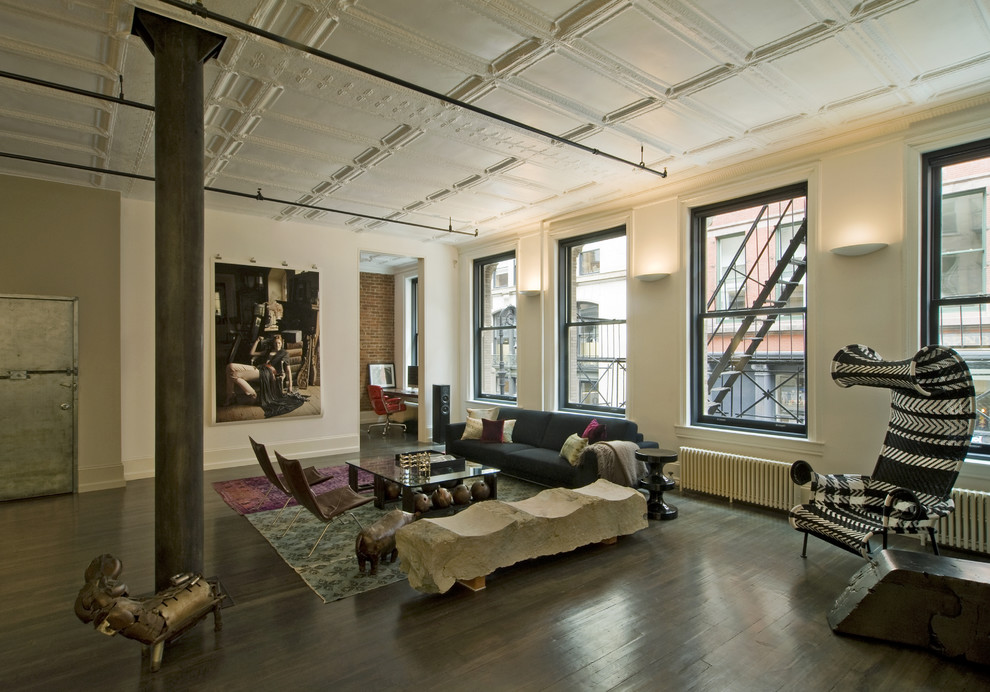 This is an example of an expansive industrial living room in New York with dark hardwood floors.