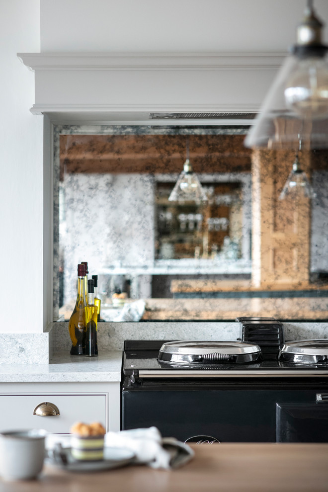 Moderne Küche in grau-weiß mit Schrankfronten im Shaker-Stil, grauen Schränken, Quarzwerkstein-Arbeitsplatte, Küchenrückwand in Metallic, Glasrückwand, Küchengeräten aus Edelstahl, dunklem Holzboden, zwei Kücheninseln, braunem Boden und weißer Arbeitsplatte in Sonstige